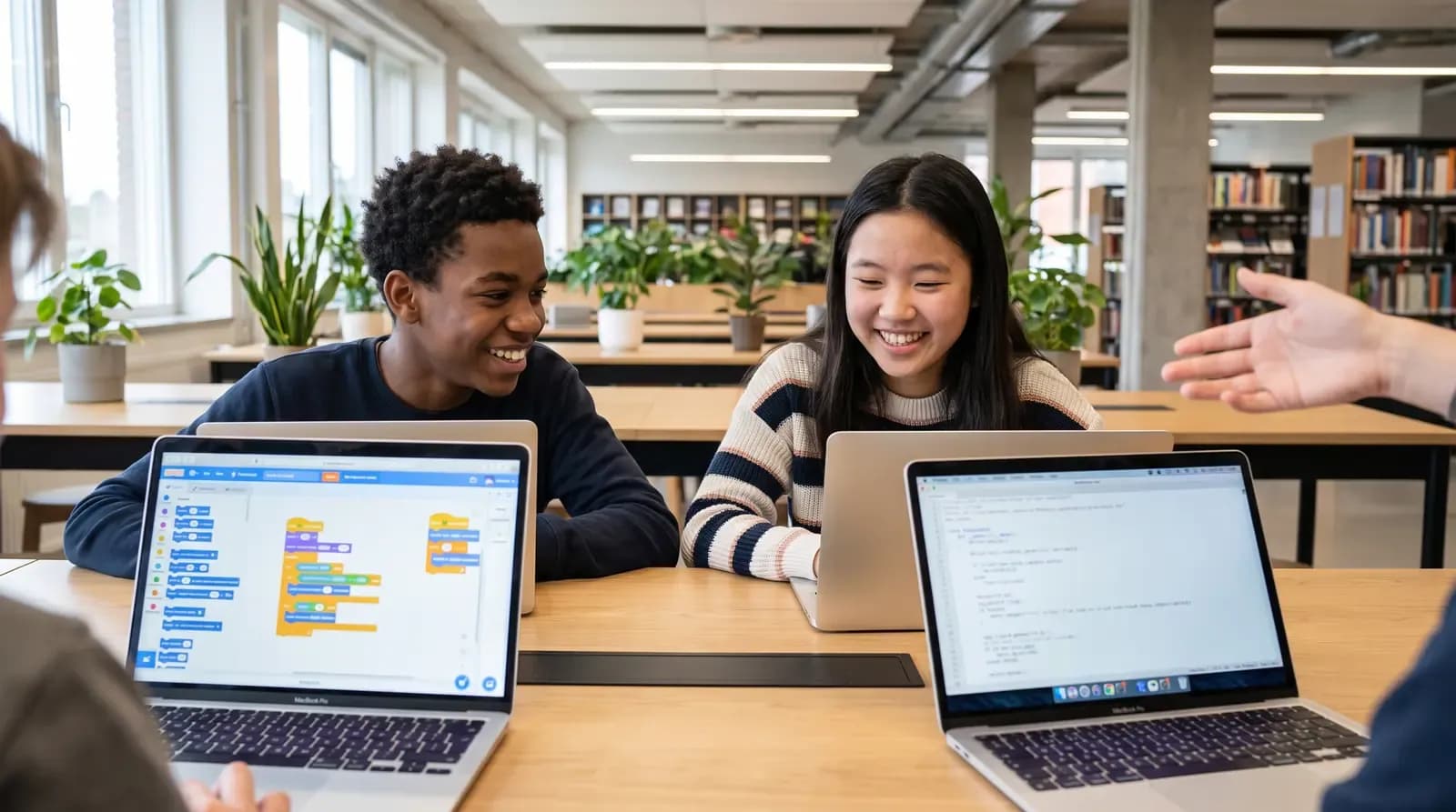 Teens coding side by side on laptops